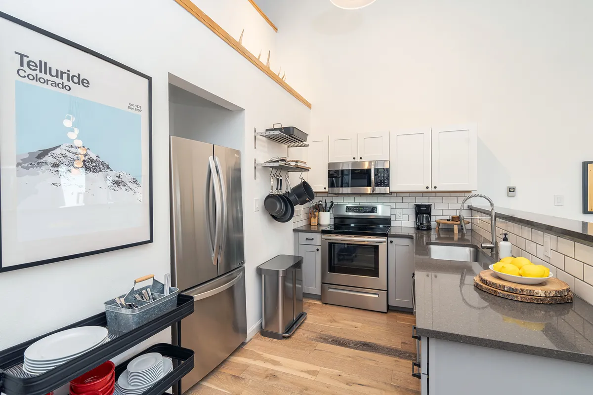 A functional kitchen with gleaming stainless steel appliances, a polished granite countertop, a vibrant fruit bowl, and tasteful wall art. The space feels ready for culinary adventures and is equipped with professional-grade features.